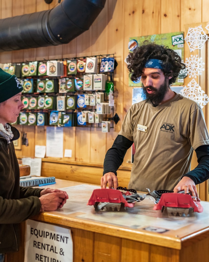 A man hands snowshoes to a visitor